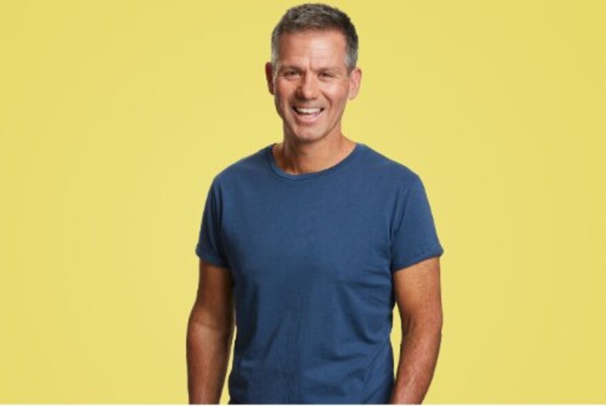Charity CEO Matt Tilley, wearing blue T-shirt with yellow background.