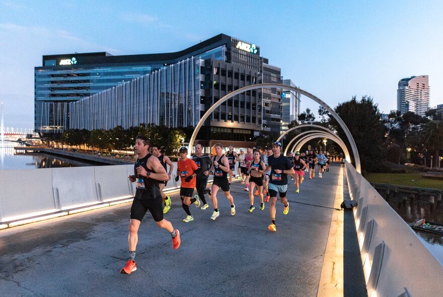 A large group of people running over a bridge during a fun run.