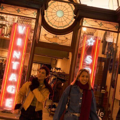 Two smiling friends, wrapped in winter scarves and wearing gloves, leaving the  clothing shop Vintage Sole located in the historic Cathedral Arcade in the Nicholas Building.