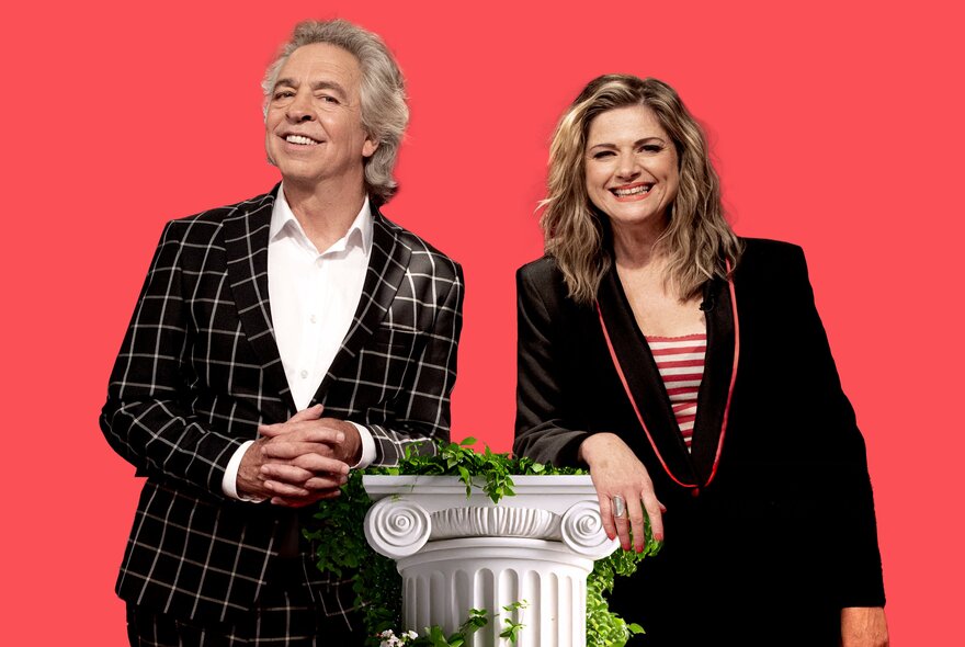 RockWiz hosts Julia Zemiro and Brian Nankervis, posed leaning on a column, against a red backdrop.