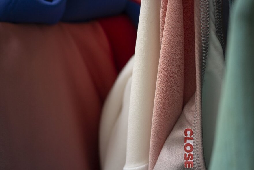 Close up of draped fabrics or garments, one with a seam and part of a tag showing. 