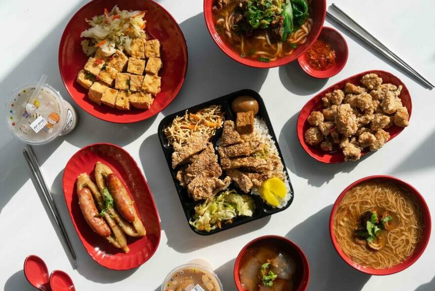 A bento box of fried chicken in the middle of a table of other fried food items.