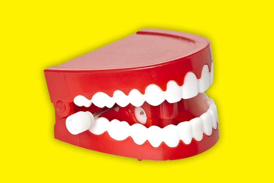 Novelty wind-up chattering teeth against a yellow background.