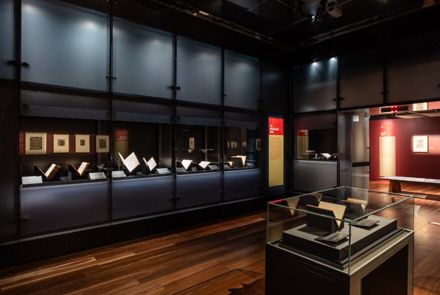 Gallery space with displays of books and framed prints in cabinets and shelves.