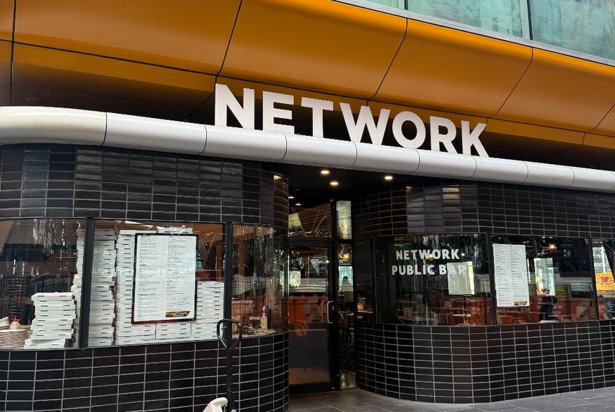 The tiled exterior of Network Sports Bar with a large sign above the doorway spelling out NETWORK in capital letters.