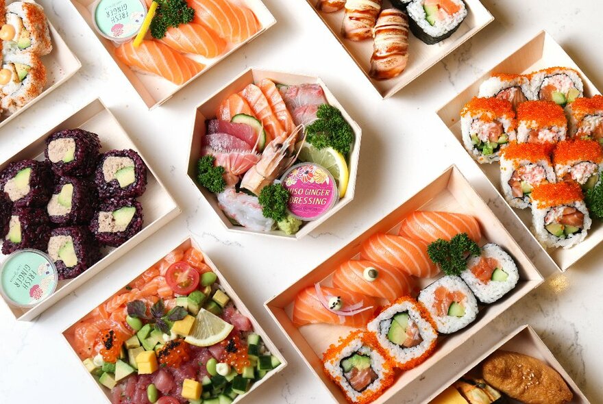 Looking down on a table featuring many different bento and sushi arrangements. 