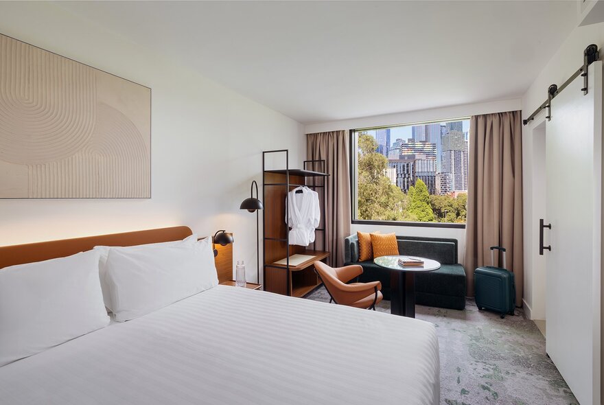 A bedroom at the Crowne Plaza Melbourne Carlton, featuring a city-view window, a king size bed, and neutral color palette.