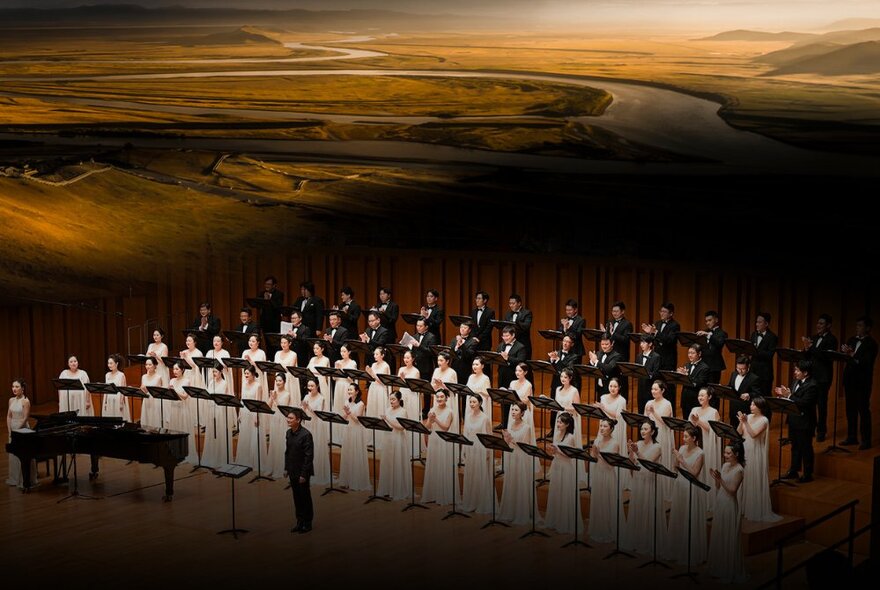 The China National Symphony Orchestra Chorus performing on a stage, the women dressed in long white dresses and the men wearing formal tuxedos. 