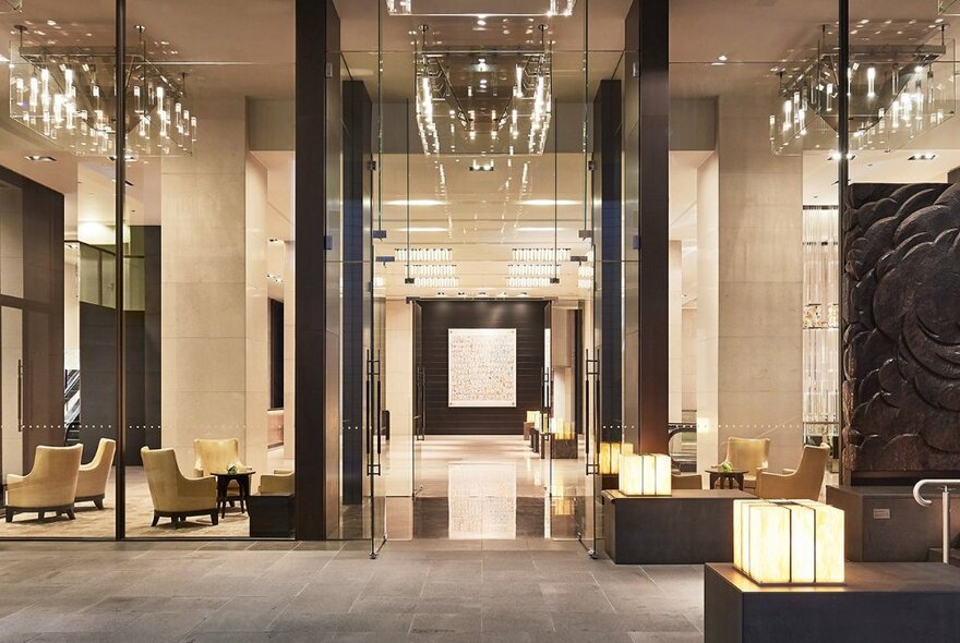 Grand hotel foyer with double-height ceilings, downlighting and armchair seating.