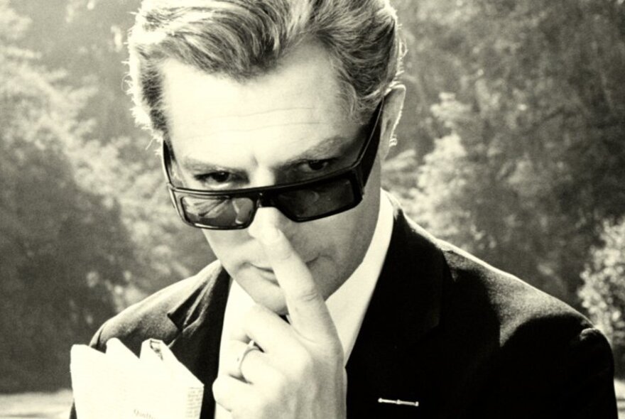 Actor Marcello Mastroianni in the 1963 film 8½, wearing a classic dark suit and sunglasses.