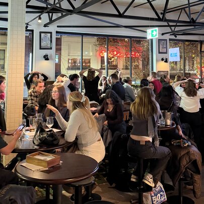 A crowd of people seated at tables inside Springrock Public Bar enjoying drinks and dining, taking part in a trivia quiz.