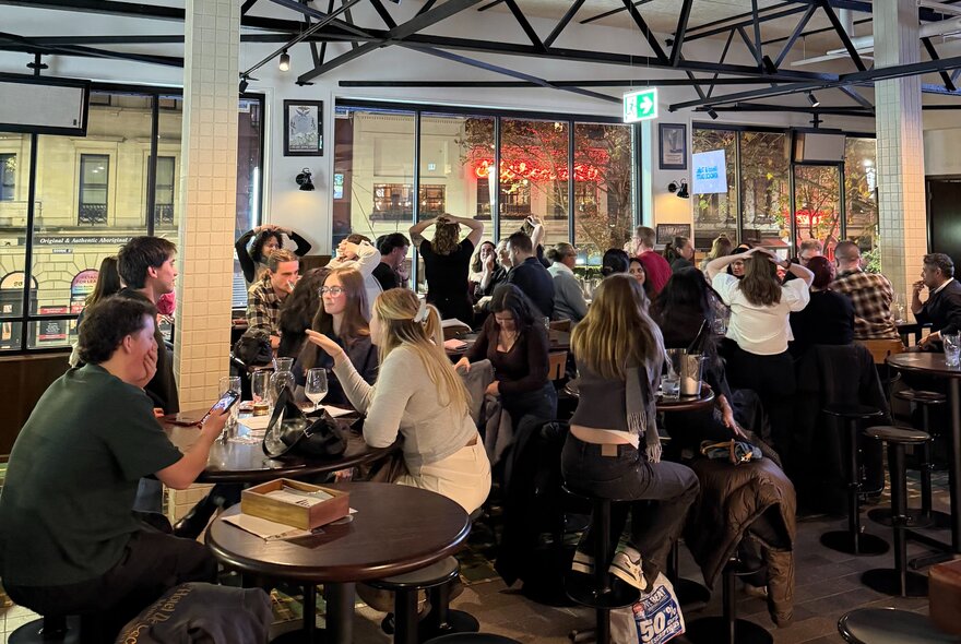 A crowd of people seated at tables inside Springrock Public Bar enjoying drinks and dining, taking part in a trivia quiz.