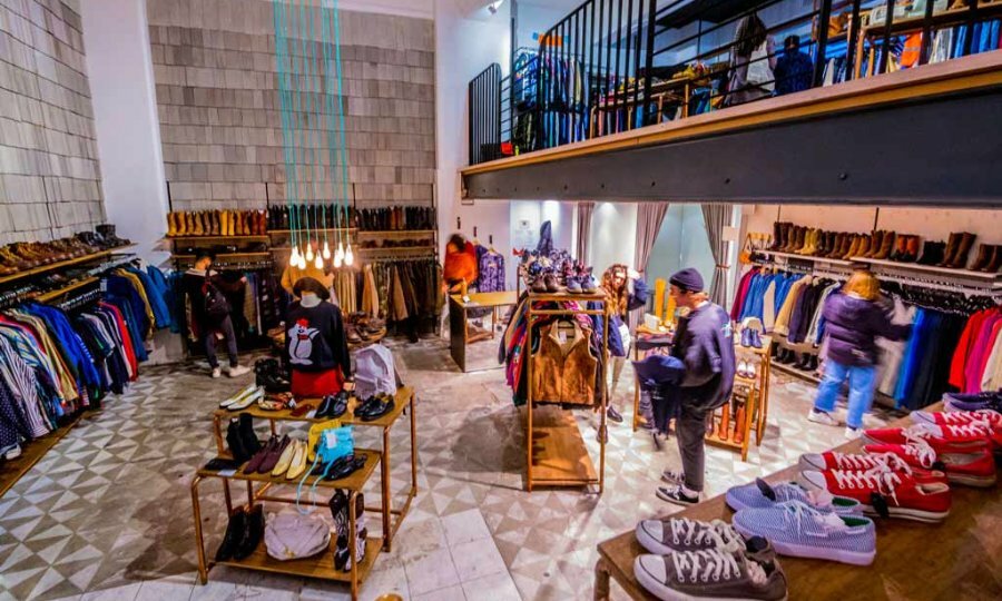 People browsing in a two storey vintage shop with curated racks of clothing. 