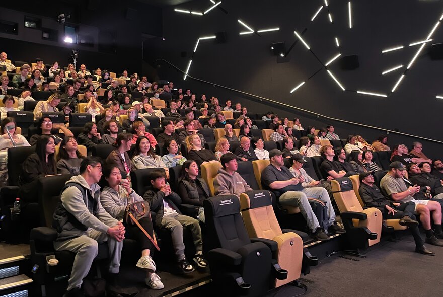Audience seated in a cinemal with the house lights up. 