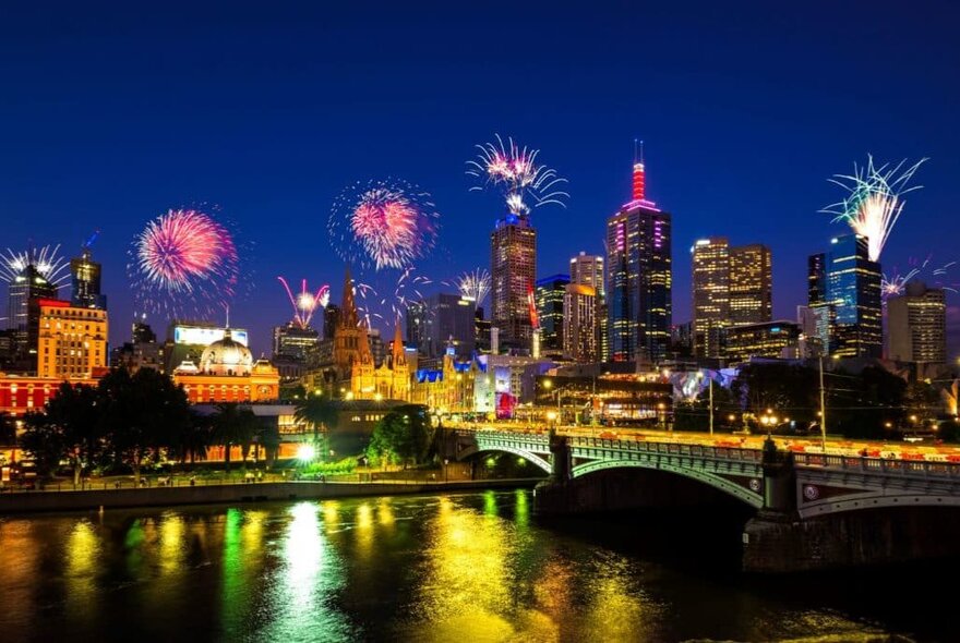 Fireworks above Melbourne's city buildings from the Yarra River's south bank.