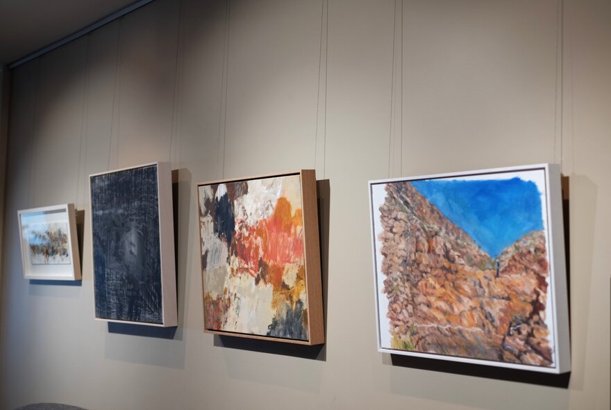 Artworks of Australian landscapes hanging on a grey wall.