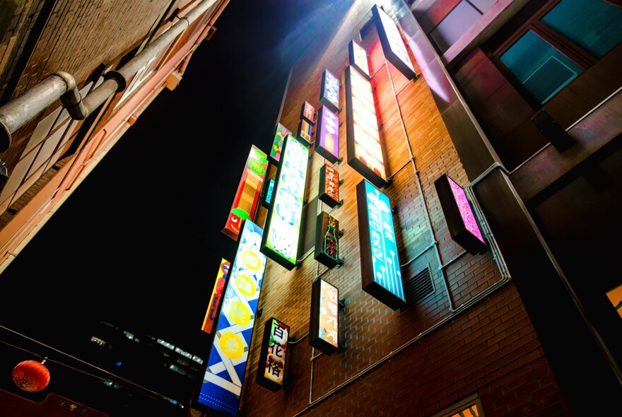 Neon street signs on one building seen from below.