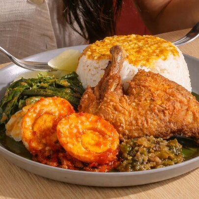 Dish of nasi kapau ayam (chicken mixed curry rice) platter, an Indonesian cuisine featuring steamed rice accompanied by various side dishes.