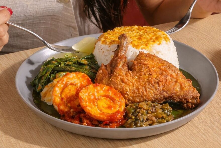 Dish of nasi kapau ayam (chicken mixed curry rice) platter, an Indonesian cuisine featuring steamed rice accompanied by various side dishes.