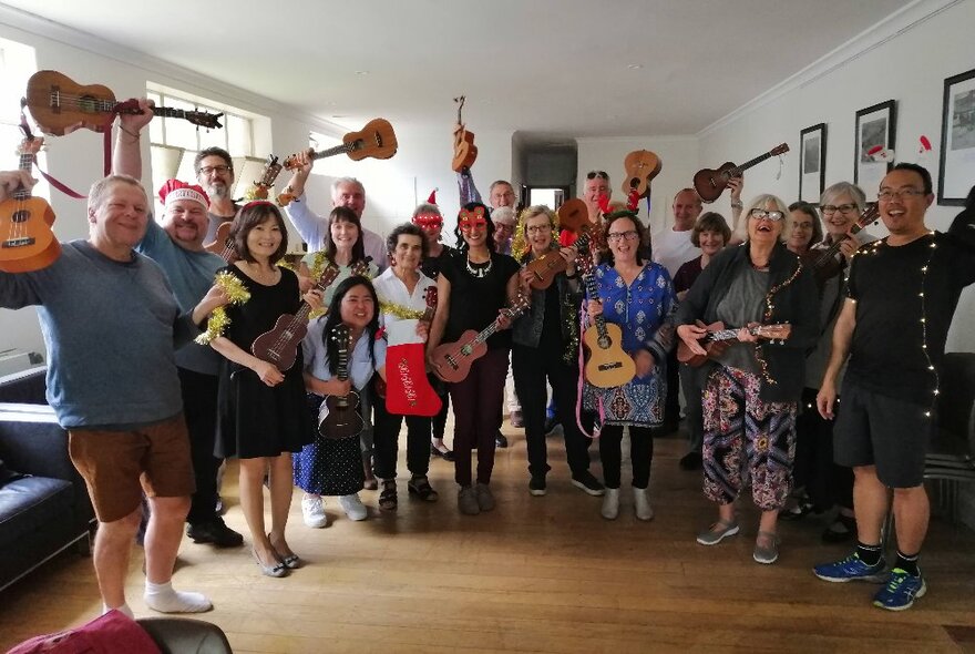 Ukulele group staning with instruments in a community hall setting.