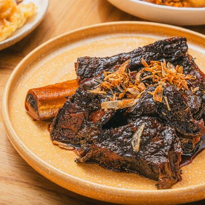 An Indonesian dish of braised beef on an orange plate.