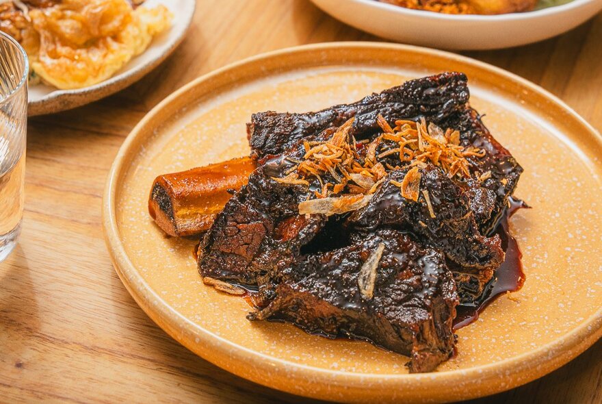 An Indonesian dish of braised beef on an orange plate.