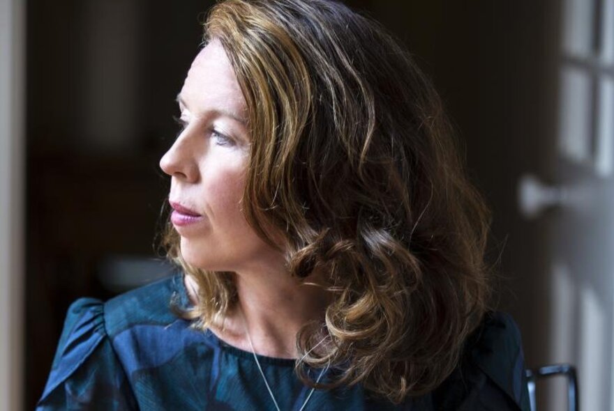 Recorder player looking to her right, with side-parted shoulder-length hair.