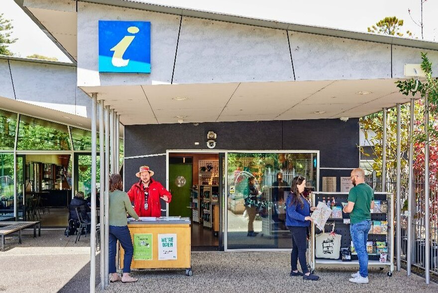 Tourist information centre, with a person in a red uniform talking to a visitor.