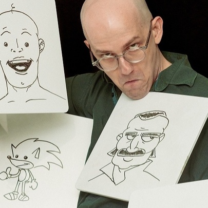 Zach Navarre  holding up drawings of people's faces and Sonic the Hedgehog, gripping one picture with his chin.