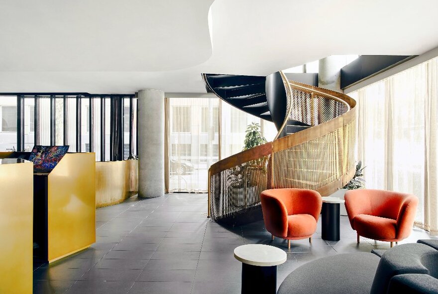 The main foyer of the Quincy Hotel Melbourne featuring a spiral staircase and pops of colour.