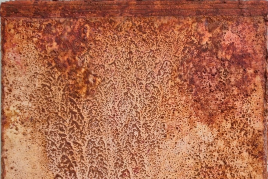 Artwork that looks like a heavily weathered, rusted surface featuring a mix of deep orange, reddish-brown, and tan tones.