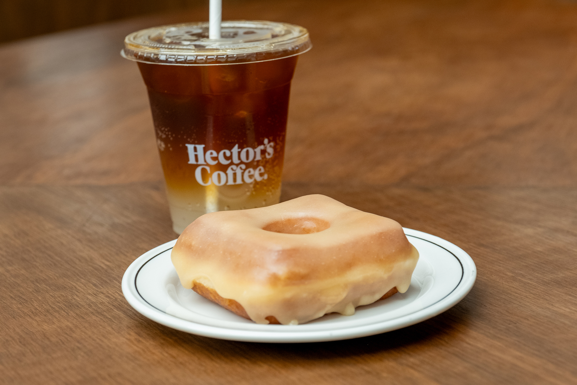 A square glazed doughnut and a takeaway iced coffee.