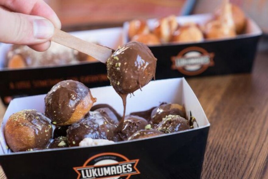 A carton with chocolate dipped lukumades.