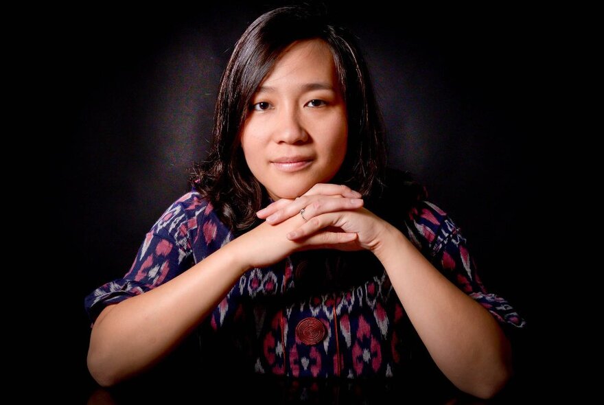 Portrait of organist Ria Angelika Polo with her hands clasped under her chin. 