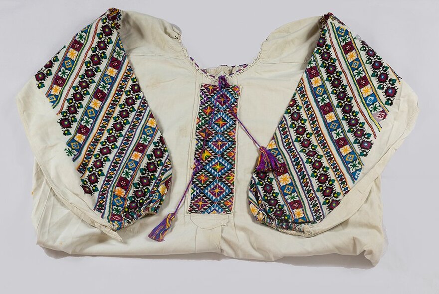 A Ukrainian white cotton top with woven tapestry detail on the long sleeves and collar. 