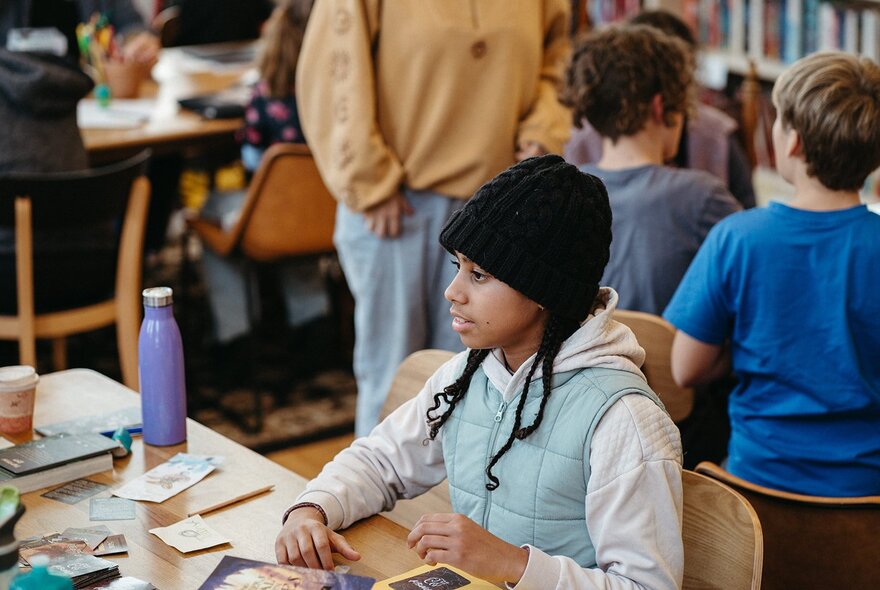 Child seated at a table with pens and paper.
