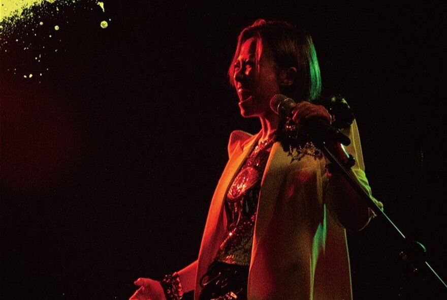 A performer on a dark stage lit by red light.
