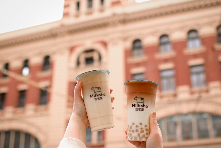 People holding up bubble teas in the city. 