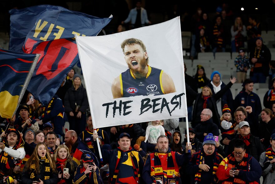 AFL fans holding banners in the stands during a match.