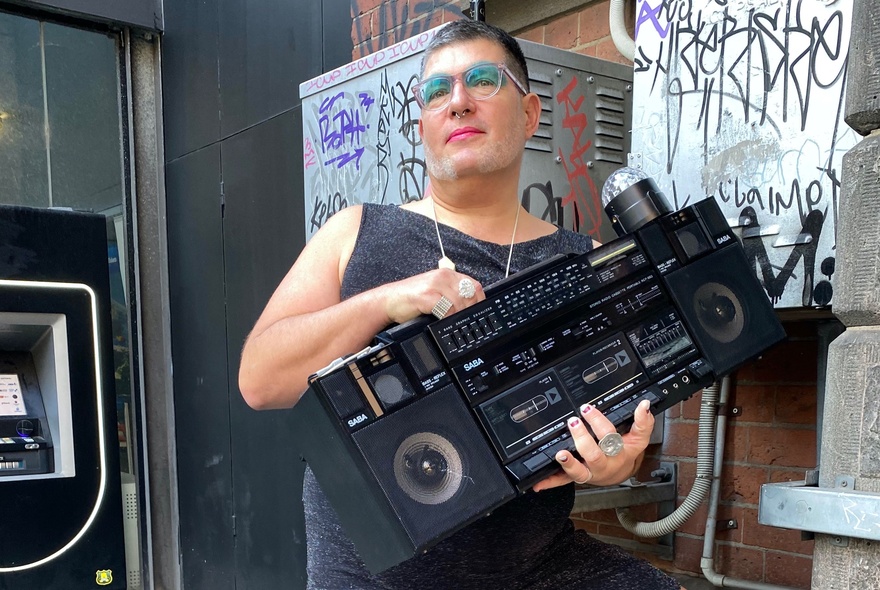 Peter Baecker wearing makeup and holding an 80s-style ghetto blaster.
