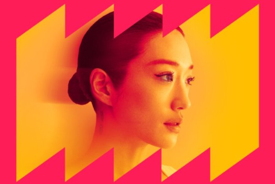 Portrait of a young Asian woman with her hair slicked back in a bun, looking to the side; yellow background with jagged pink framing.