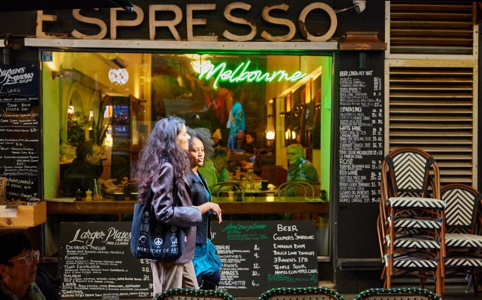 Two people walking past an old-school coffee window.