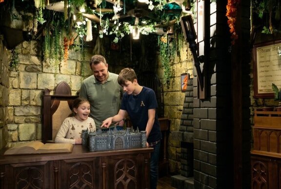 A Dad with tow children playing a game at an escape room.