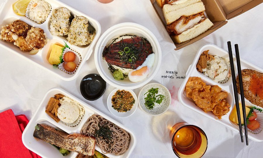 A selection of bento boxes and Japanese dishes in takeaway containers. 