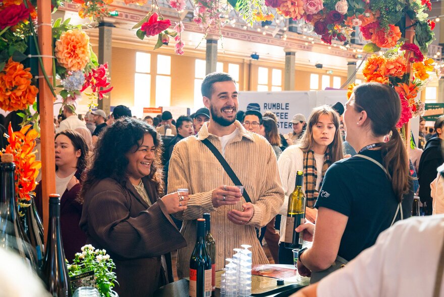 People browsing a designer craft stall and talking to the stallholder at the Big Design Market inside the Royal Exhibition Building.