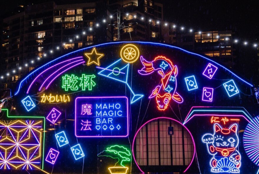 Japanese-inspired neon signs under twinkling lights and city buildings at night.