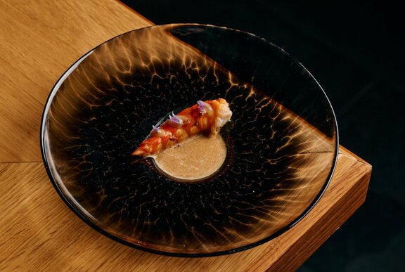 Dark dish of exquisitely presented Japanese seafood, on a dark background.