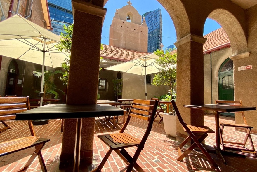 The courtyard at Mission to Seafarers building, with tables and chairs, and an arched colonnade.