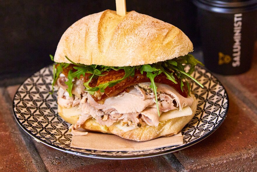 A close-up of a panini full of deli meat, cheese and rocket.