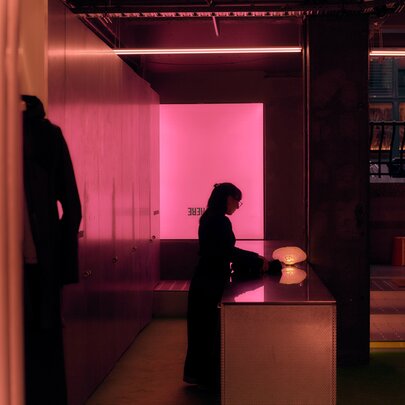 Interior of Up There retail space features minimalist design elements, including a bright pink glowing wall and a central counter.